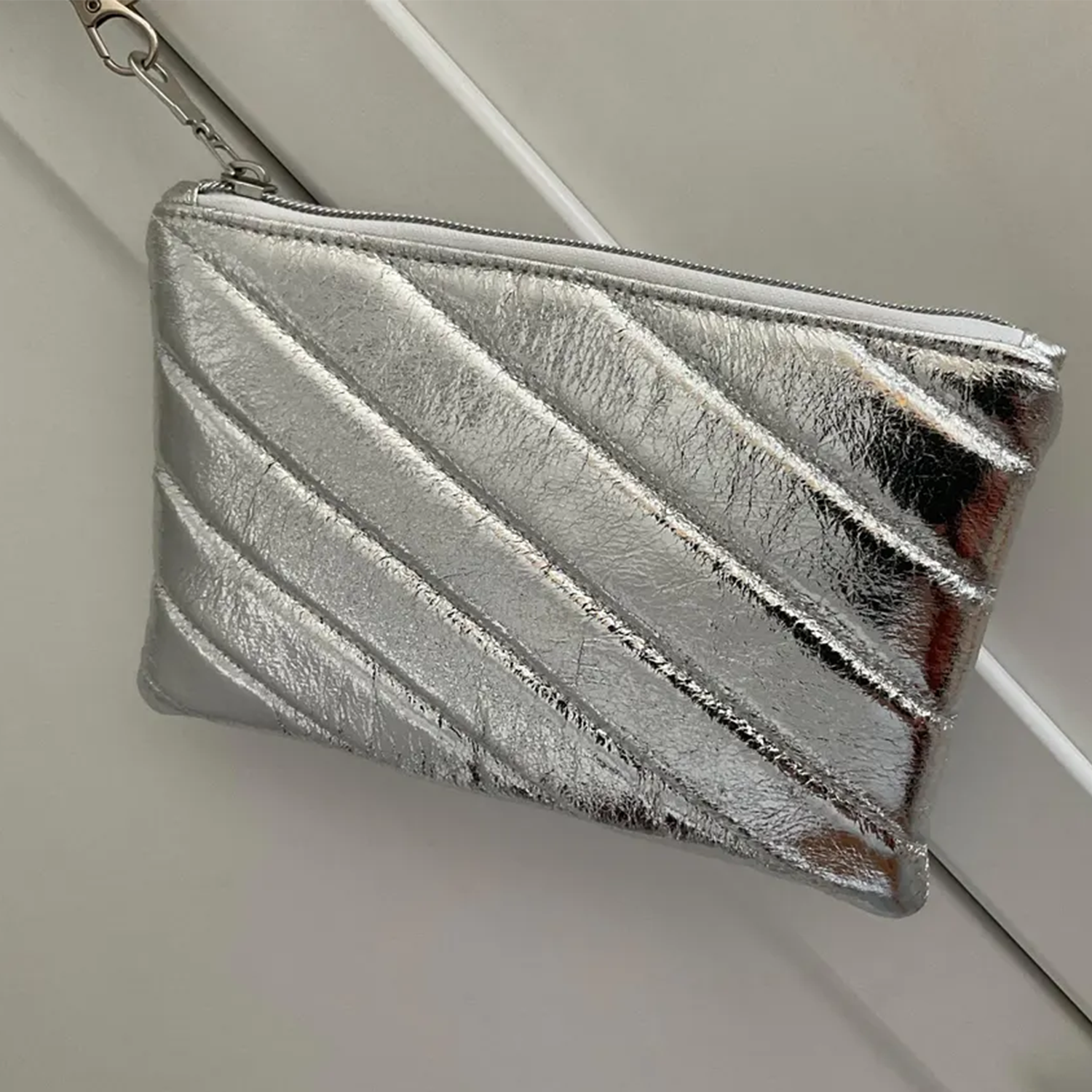 Metallic Silver Diagonal Quilted Padded Zip Pouch With Detachable Wrist Loop Strap And Swivel Metal Clasp Hardware